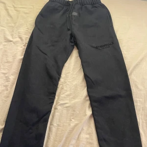 Svarta mjukisbyxor Essentials  - Svarta mjukisbyxor från Essentials Fear of God med broderad logga på benet. Använd rätt så mycket och är lite slitna men fortfarande rätt så bra skick. Storlek S, män. Pris kan diskuteras. Skickar inom 1-3 dagar.