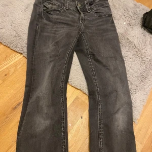 Svarta bootcut jeans från Gina Tricot - Snygga svarta jeans från Gina Tricot i bootcut-modell. Jeansen har klassiska fem fickor, markerade sömmar och en något utsvängd passform nertill. Perfekta för dig som gillar en tidlös look med lite edge.