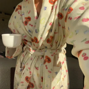 morgonrock med fruktmönster - Supermjuk morgonrock från Djerf avenue med färgglatt fruktmönster i orange, rosa, blått och grönt. Modellen har sjalkrage, knytskärp i midjan och stora fickor. Perfekt för chilliga morgnar eller mysiga kvällar hemma.