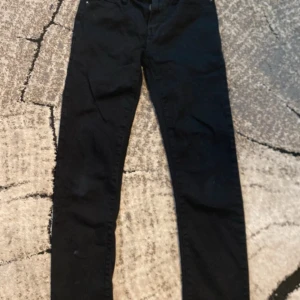 Svarta skinny jeans från Denimday, 146 - Svarta jeans från Denimday i storlek 146. Modellen är skinny med smal passform och klassisk femficksdesign. Jeansen har bälteshällor och är gjorda i ett stretchigt bomullsmaterial som sitter snyggt och bekvämt. Perfekt för dig som gillar en stilren look.