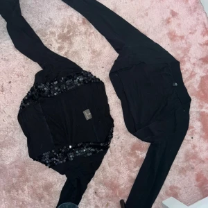 Mix av koftor och boleros i olika färger - Fyra olika koftor och boleros: svart med paljettdetaljer, svart enkel, beige stickad med spetskant, vit enkel, röd med knutdetalj och vit med knappar och hålmönster. Perfekt för att lyfta din outfit med olika stilar och färger.