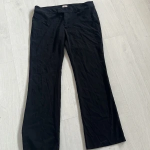 Svarta kostymbyxor från Nelly - Svarta kostymbyxor från Nelly med klassisk rak passform och diskret stängning fram. Byxorna har en stilren look och är tillverkade i ett mjukt tyg som känns bekvämt. Perfekta för dig som gillar en clean och enkel stil.