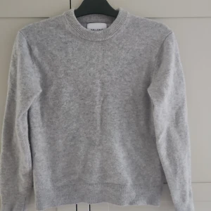 Ljusgrå merinoulltröja från Vailent - Säljer en stilren ljusgrå tröja från Vailent i mjuk merinoull. Tröjan har rund halsringning, ribbade muddar och lång ärm. Perfekt för lager-på-lager och enkel att matcha med jeans eller kjol. Det är storlek S fast passar till XS