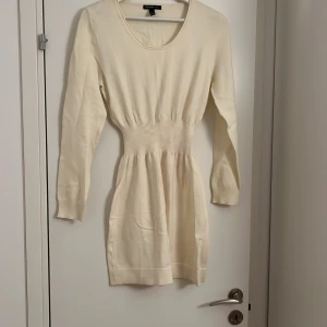 Krämvit stickad kort klänning Mango - Supersöt krämvit stickad klänning från Mango med rund hals och långärmad design. Smickrande ribbad midja som ger en snygg siluett. Perfekt för dig som gillar enkel och stilren look med mjukt material. Är liten i storlek passar mer s-m tycker jag.