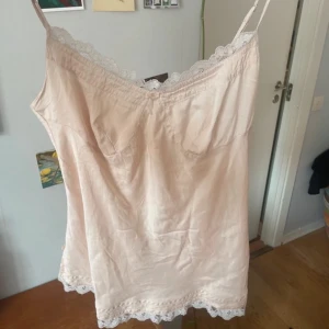 Ljusrosa kort klänning med spets - Söt ljusrosa topp  med tunna axelband och spetsdetaljer längs halsringning och nederkant. 