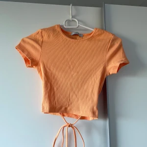 Orange croppad topp med knyt XS - Superfin orange croppad topp med korta ärmar och knytband i midjan. 