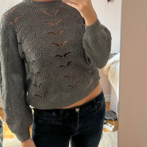 Grå stickad tröja med hålmönster - Säljer en grå stickad tröja med snyggt hålmönster och rund hals.