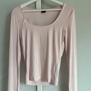 Ljusrosa långärmad topp Gina Tricot - Supersöt ljusrosa långärmad topp från Gina Tricot med rundad, djup urringning. Tunn och mjuk i materialet, perfekt att styla med jeans eller kjol. Enkel och stilren design som funkar till många olika looks.