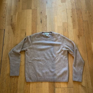 Beige kashmirtröja från COS - Supermjuk kashmir beige tröja från COS i 100% kashmir. Klassisk rund halsringning, ribbade muddar och långärmad modell. Perfekt för dig som gillar stilren och enkel design med lyxig känsla. Passar dig som vill ha en tidlös och clean look.