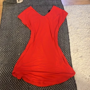 Röd klänning från Gina Tricot - Säljer en röd klänning från Gina Tricot i storlek XS. Klänningen har v-ringning och korta ärmar, med en mjuk och följsam passform. Perfekt för dig som gillar enkel och stilren design.