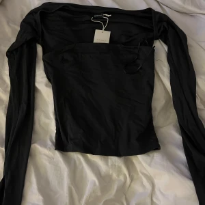 Svart långärmad offshoulder topp från Gina Tricot - Trendig svart långärmad topp från Gina Tricot med offshoulder-design. Tunn och mjuk, snygg passform och enkel att matcha med olika outfits. Tröjan är helt oanvänd med prislapp🥰