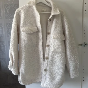 Vit teddyjacka med knappar från HM - Vit teddyjacka med stora knappar framtill och två bröstfickor.