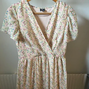 Blommig omlottklänning - Söt ljusbeige omlottklänning från H&M, används en gång och är i perfekt skick.🤍