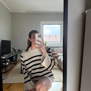 Beige och svart randig stickad tröja - Säljer en beige stickad tröja med svarta horisontella ränder. Tröjan har lång ärm och en avslappnad, loose passform. Perfekt för en chill och stilren look.