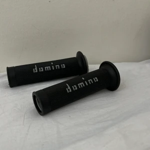 Hantag domino - Hantag från domino perfekt för mopeder och crossar för att fräscha upp looken på fordonet! Skick 10/10 Nyskick säljer för dom inte passa moppen högra sidan: 24mm och vänstra 22mm