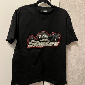   Trapstar  t-shirt - Säljer en svart t-shirt från Trapstar med broderad text och pantermotiv på bröstet. T-shirten har rund halsringning och korta ärmar. Perfekt för dig som gillar streetwear och vill sticka ut med en snygg logga. Helt äkta