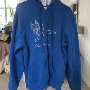 Best yet to come hoodie - Säljer en best yet to come hoodie med dragkedja och huva. På framsidan finns ett tryck i strass med en ängel som skjuter pilbåge mot ett gevär, Perfekt för dig som vill sticka ut med en unik design.