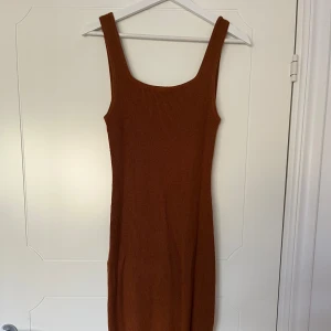 Figursydd sommarklänning  - En varm brun aktig sommar klänning som sitter otroligt mot kroppen, i stretch. Finns slits på båda sidorna av benen nedtill.