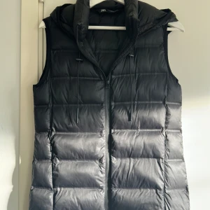 Svart dunväst med huva - Säljer svart Zara väst, relativt gott skick. Västen har ett quiltat mönster och dragsko vid huvan. Perfekt för lager-på-lager och funkar till många olika outfits. Pris kan diskuteras.