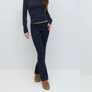 Marinblå yoga pants med utsvängda ben - Säljer ett par marinblå yoga pants med nedvikbar midja och utsvängda ben. Byxorna är i mjukt och stretchigt material, perfekta för en avslappnad stil. Passar dig som gillar bekväma och trendiga byxor. Dom är avklippta längst ner så dom är bra i längd för mig som är 160. Så passar dig om du är kort