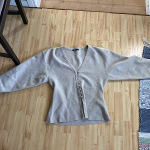 Beige kofta med v-ringning och knappar - Säljer en beige kofta med v-ringning och knappar framtill. Använt en gång 