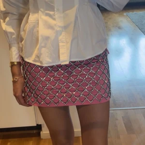 Rosa minikjol med pärldetaljer från H&M - Säljer en rosa minikjol från H&M med glittriga pärldetaljer i rutmönster. Perfekt statement piece för dig som vill sticka ut! Helt ny med prislapp kvar, nypris 699!!!