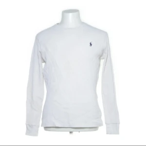 Vit långärmad tröja från Polo Ralph Lauren - Klassisk vit långärmad tröja från Polo Ralph Lauren med liten broderad logga på bröstet. Tillverkad i 100% bomull med en enkel och stilren design. Perfekt för en clean och avslappnad look.