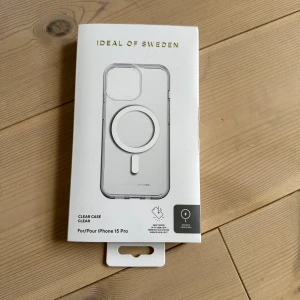 Transparent mobilväska från iDeal of Sweden - Säljer ett genomskinligt mobilskal från iDeal of Sweden, designat för iPhone 15 Pro. Skalets design är stilren och minimalistisk med en rund MagSafe-ring på baksidan. Perfekt för dig som vill visa upp din mobil och samtidigt skydda den. säljer då jag köpte fel modell.