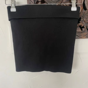 Svart ribbad tubtop från BikBok - En svart, tight ribbad tubtop från BikBok. Topen har en enkel och stilren design med bred linning och stretchigt material som sitter snyggt på kroppen. Perfekt att matcha med en kostymbyxor eller kjol. (Storleken är väldigt liten)