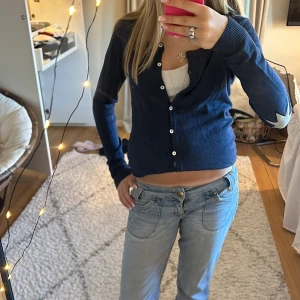 Mörkblå kofta med stjärndetaljer - Mörkblå kofta med vita knappar och vita stjärnor på ärmarna. 