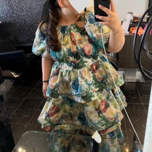 Blommig volangklänning med puffärm - Säljer min superfina balklänning. Klänningen har endast används under en kväll och är i helt nytt skick. Skriv vid frågor.