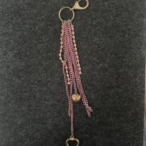 Nyckelring med rosa kedjor och hjärtan - Säljer en unik nyckelring med flera rosa kedjor och två hjärtformade detaljer i metall. Kedjorna har små glittriga stenar och ger ett coolt och trendigt intryck. Perfekt accessoar till väskan eller nycklarna!