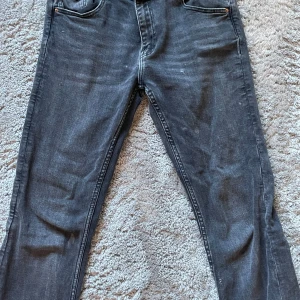 Svarta jeansbyxor från ZARA - Säljer ett par svarta jeansbyxor från ZARA med klassisk femficksdesign och utsvängda ben. Jeansen har normal passform och är tillverkade i denim med lätt tvättad look. Perfekta till vardags och enkla att matcha med olika stilar.