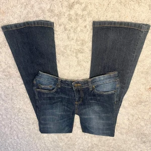Marinblå utsvängda jeans från John Baner - Snygga marinblå utsvängda jeans från John Baner. Perfekt passform med en midjemått på cirka 39 cm och en innerbenslängd på cirka 80,5 cm. Dessa jeans har en klassisk design med fem fickor och snygga sömdetaljer på bakfickorna.