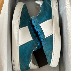 Blå Valentino Flycrew sneakers  - Säljer ett par snygga valentino flycrews i storlek 42. Skorna saknar flertalet nitar men är utöver det i bra skick och sparsamt använda. Box och extra skosnören tillkommer även! 