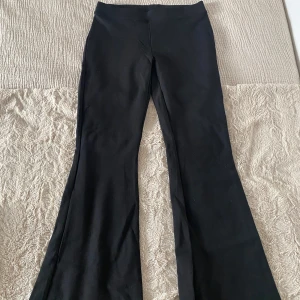 Svarta bootcut byxor från Gina Tricot - Svarta bootcut byxor från Gina Tricot med hög midja och stretchigt material. Perfekta för en trendig och bekväm look. Byxorna har en enkel design utan synliga detaljer och är lätta att matcha med olika toppar.