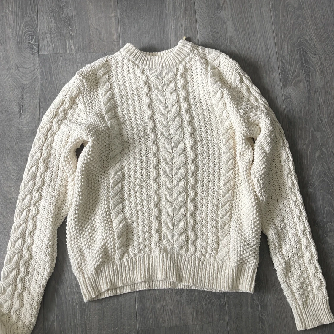 Vit stickad tröja med flätmönster