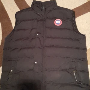 Svart dunväst från Canada Goose - Säljer då den är för stor för mig. Defekter: fickorna har haft hål på insidan men är igensydda, ingenting som syns. Skriv för mer bilder😁 Priset är ej hugget i sten!