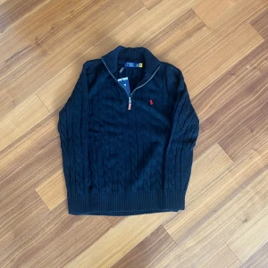 Polo Ralph Lauren Halvzip Tröja (Ny med tagg) – Storlek L - Säljer en helt ny svart kabelstickad tröja från Polo Ralph Lauren i modell med halv dragkedja. Klassisk och tidlös design, perfekt till både vardag och finare tillfällen.  ✔️ Märke: Polo Ralph Lauren ✔️ Storlek: L ✔️ Färg: Svart ✔️ Skick: Ny, med tagg kvar ✔️ Modell: Halvzip / Quarter-zip ✔️ Material: 100 % bomull ✔️ Detalj: Röd broderad logga på bröstet 📦 Skickas spårbart eller kan hämtas upp 💬 Pris kan diskuteras vid snabb affär  🎁 Perfekt som present