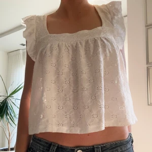 Volang broderi linne  - Säljer somrigt vitt linne med broderi detaljer och volangarmar från Gina tricot 💖använd väldigt få gånger då de är fel storlek för mig💗skriv vid frågor 