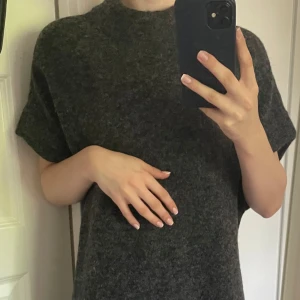 Mörkgrå stickad tröja från Fransa - Mysig mörkgrå stickad tröja från Fransa med korta ärmar och rund halsringning. Tröjan har en avslappnad passform. Tillverkad av ett värmande material. Tröjan är ej använd och jag säljer den då jag inte hittar användningstillfällen.