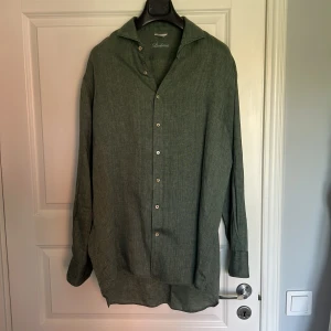 Grön linneskjorta från Stenströms - Snygg grön skjorta i linne från Stenströms med klassisk krage och knappar framtill. Skjortan har lång ärm och diskret broderad logga vid nederkanten. Perfekt för en stilren och avslappnad look. Fitted body stl XL. 