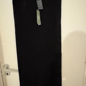 Svart stickad ärmlös långklänning från H&M - Svart stickad långklänning från H&M med rund halsringning och ärmlös design. Klänningen har ett genombrutet stickat mönster som ger en luftig känsla. Har inte använts en enda gång helt ny!