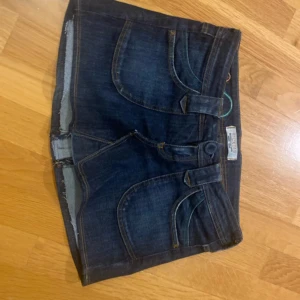 Mörkblå jeanskjol med broderade cirklar från SICK019 - Snygg mörkblå jeanskjol med rå kant och broderade cirklar i grönt, lila och orange. Klassisk femficksmodell med knapp och dragkedja. Perfekta för sommaren och enkel att matcha med olika toppar. Är hemmasydd.