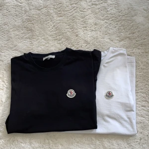 Moncler T-shirts 2x - Två klassiska t-shirts från Moncler, en svart och en vit, båda med Monclers ikoniska logga broderad på bröstet. T-shirtsen har rund hals och är tillverkade i mjuk bomull. Perfekta för en clean och stilren look. Passar både S och M beroende kroppsform.                                                                • båda för 1200 eller 1 för 700kr