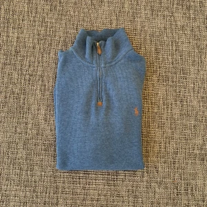 Blå halvzip tröja från Ralph Lauren - Snygg blå långärmad Ralph Lauren tröja med half, knappt använd då jag växte ur den. Jag har sytt om den också till en bättre passform då jag tyckte den vikte ut för mycket vid nedre delen innan.