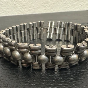 Vintage metallarmband – Retro 60-/70-tal med brutalistisk länkdesign - Vintage armband i silvrig metall, troligen från 60- eller 70-talet. Ca 18 cm långt och 1,5 cm brett. Består av ledade länkar med rå finish och mörkare partier – en tydlig brutalistisk design. Stängs med snäpplås. Fint skick med snygg patina. Perfekt för dig som gillar retro, rockig stil eller kraftfulla accessoarer. Prutning accepteras ej, men jag erbjuder rabatt vid köp av flera saker. Rensar garderoben – kolla gärna mina andra annonser också!  ⸻  