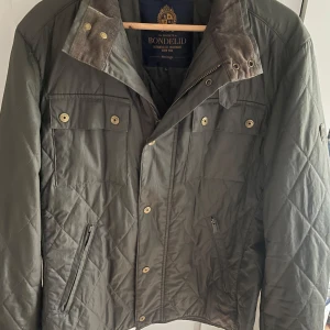 Olivgrön quiltad jacka från Bondelid - Säljer en olivgrön quiltad jacka från Bondelid i storlek L. Jackan har dragkedja och knappar framtill, två bröstfickor med knapp och två sidofickor med dragkedja. Klassisk krage med manchesterdetalj. Saknar en knapp