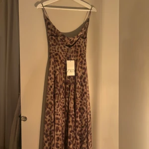 Leopardmönstrad långklänning från Zara - Säljer en snygg helt oanvänd långklänning i leopardmönster från Zara som är helt slutsåld och var väldigt trendig förra sommaren! Klänningen har tunna axelband, en draperad urringnin och djup rygg, storlek S med lappen kvar🤎🤍 Även superfin att ha en stickad tröja över om man föredrar att ha den som kjol🤩(Sista bilden är lånad)