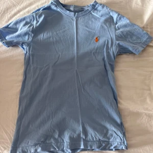 Ljusblå Ralph Lauren T-shirt  - Jättefint skick, knappt använd. Storlek 10 år
